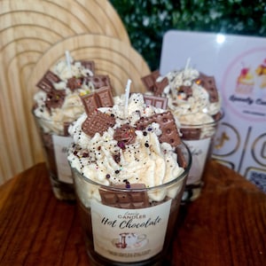 Puede incluir: Tres velas de cristal rellenas de cera marr&oacute;n oscuro, cubiertas con cera blanca batida que parece nata, decoradas con peque&ntilde;as piezas de cera con forma de tableta de chocolate y galleta, y espolvoreadas con purpurina. Etiqueta Hot Chocolate.