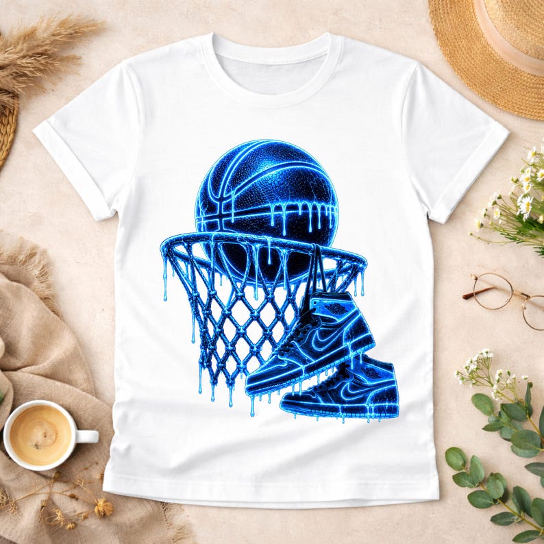 May include: A white short-sleeved t-shirt featuring a graphic print of a basketball and a basketball hoop with two high-top sneakers hanging from the rim. The entire design is rendered in a vibrant, glowing blue color with a dripping effect.
