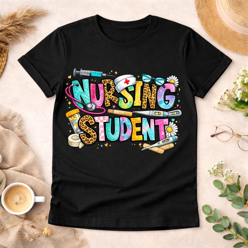 May include: Black t-shirt featuring the text "NURSING STUDENT" in a vibrant, tie-dye font. The design incorporates medical instruments such as a stethoscope, syringe, thermometer, and medicine bottle, with daisy details.