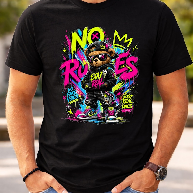 May include: Black t-shirt featuring a cartoon teddy bear wearing sunglasses, a black hoodie, and sneakers. The bear is in front of graffiti-style text that reads "NO RULES" and "STAY REAL". The shirt has a vibrant, colorful design.