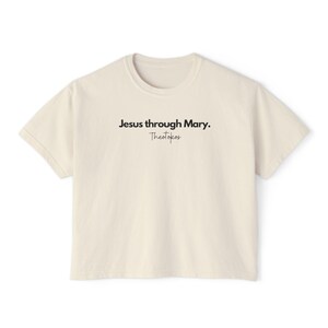 May include: A cream colored t-shirt with the text "Jesus through Mary. Theotokos" printed on the front.