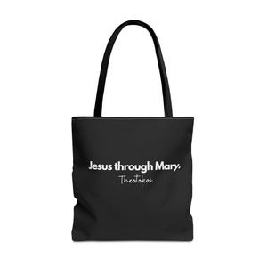 May include: Black tote bag with black handles. The bag features the text "Jesus through Mary. Theotokos" in white. The bag is designed for carrying items and has a simple, elegant design.