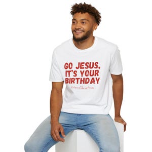 May include: White t-shirt with the red text "GO JESUS, IT'S YOUR BIRTHDAY" and the hashtag "#MerryChristmas". The shirt is worn by a person in blue jeans.