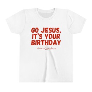 May include: White t-shirt with the red text "GO JESUS, IT'S YOUR BIRTHDAY" and the hashtag "#MerryChristmas". The shirt has a crew neck and short sleeves. A festive holiday tee.