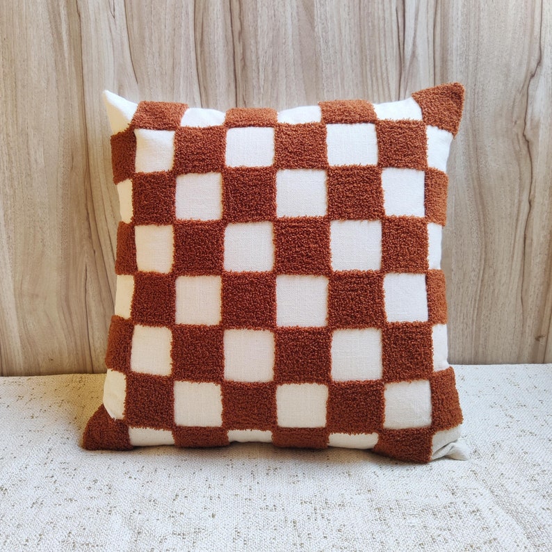 May include: A brown and white checkered throw pillow with a soft, fuzzy texture.