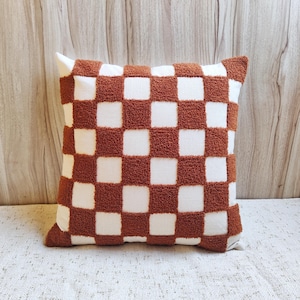 May include: A brown and white checkered throw pillow with a fuzzy texture.