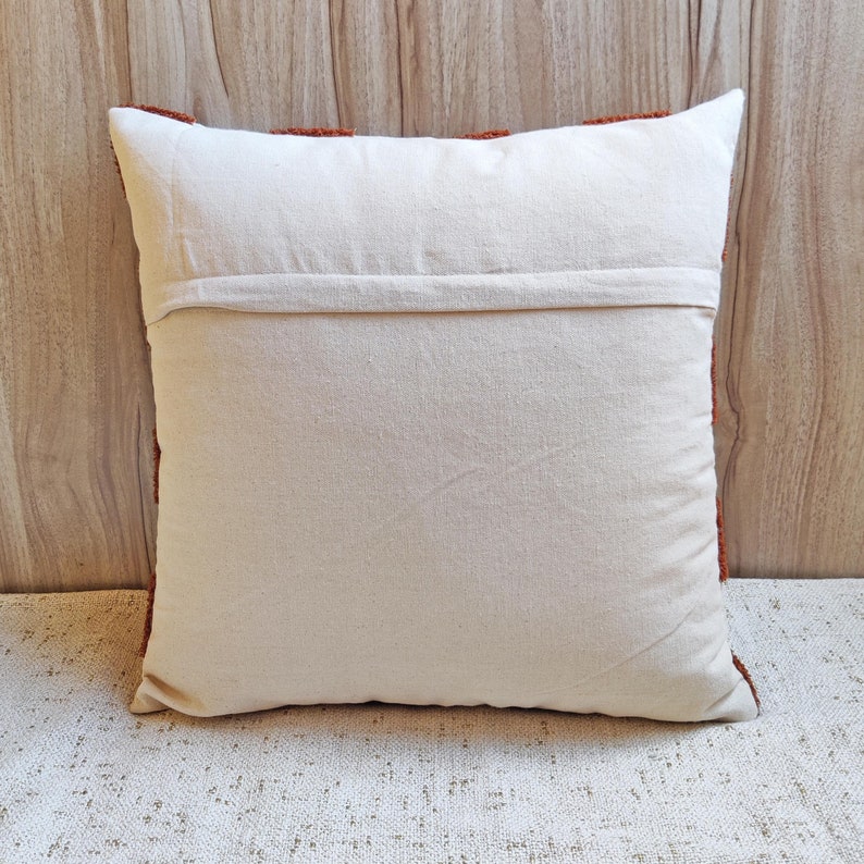 May include: A white cotton pillow cover with a brown fringe border. The pillow cover has a zipper closure on the back.