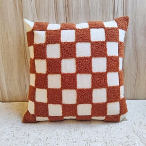 May include: A brown and white checkered throw pillow with a soft, fuzzy texture.