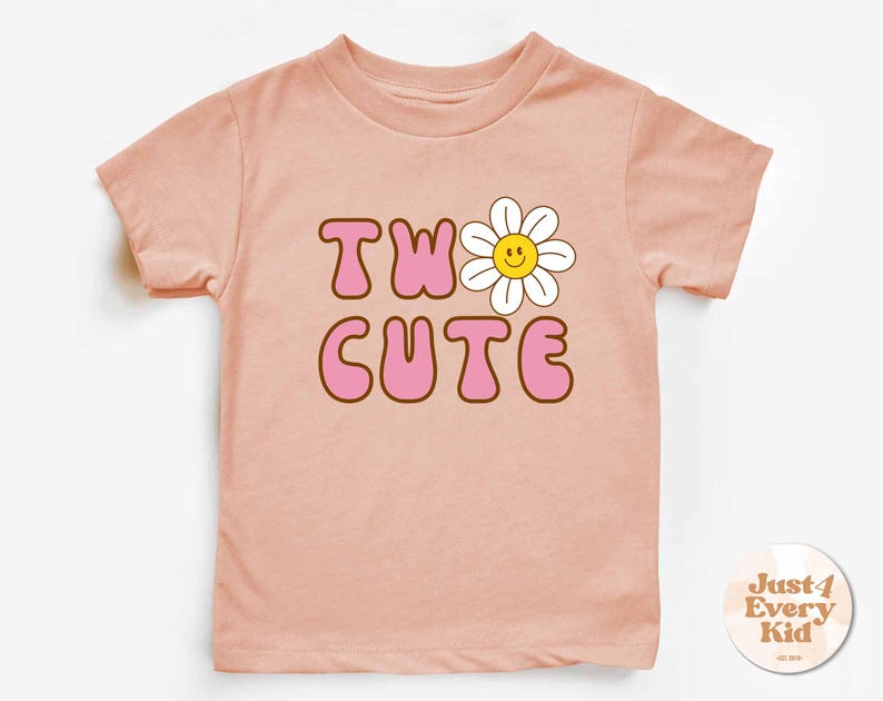 May include: A light pink t-shirt with the words "TWO CUTE" in pink bubble letters with a brown outline. A white daisy with a yellow smiling face is above the word "CUTE".