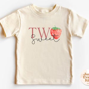 May include: A white t-shirt with a pink graphic that says "Two Sweet" with a strawberry illustration.