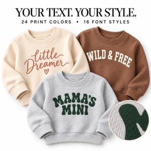 Könnte beinhalten: Drei langärmelige Rundhals-Sweatshirts in Creme, Braun und Grau meliert. Das cremefarbene Sweatshirt zeigt den Schriftzug 'little DREAMER' mit einem Herz. Das braune Sweatshirt trägt 'WILD & FREE'. Das graue Sweatshirt zeigt 'MAMA'S MINI'.