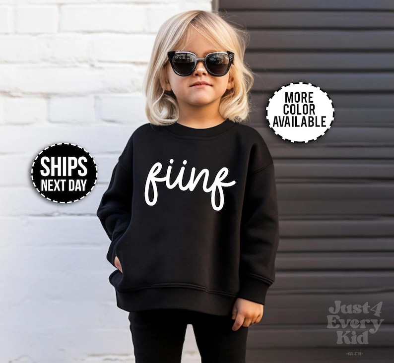 May include: A black sweatshirt with the word "fiing" in white script. The sweatshirt is worn by a child wearing sunglasses. The image also includes a "More Color Available" and "Ships Next Day" graphic.