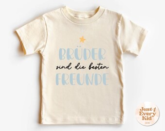 May include: A cream colored t-shirt with short sleeves and a blue and black graphic that says "Bruder sind die besten Freunde" with a small yellow star above the text.