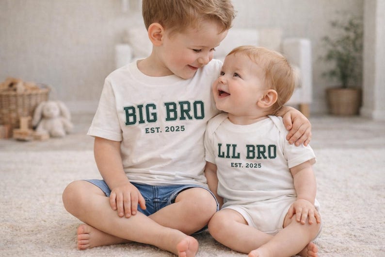 Puede incluir: Una camiseta blanca de manga corta con el texto verde oscuro BIG BRO EST. 2025 y un body blanco de manga corta con el texto verde oscuro LIL BRO EST. 2025. Ambas prendas cuentan con cuello redondo y un dise&ntilde;o sencillo y limpio.