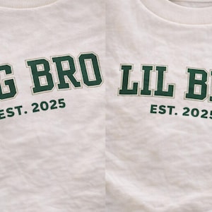 Puede incluir: Dos camisetas de color blanco roto con letras de color verde oscuro en estilo universitario. La camiseta de la izquierda muestra el texto BIG BRO EST. 2025, mientras que la de la derecha muestra el texto LIL BRO EST. 2025. Ambas tienen cuello redondo.