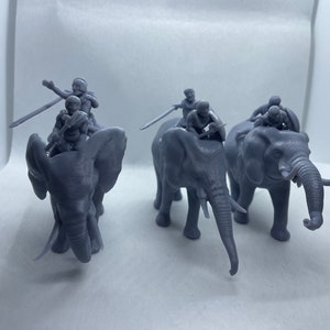 May include: A collection of gray miniature elephant figurines, each carrying multiple small figures with swords. The elephants are in various poses, with trunks and tusks visible. The figures are detailed, suggesting a historical or fantasy theme.