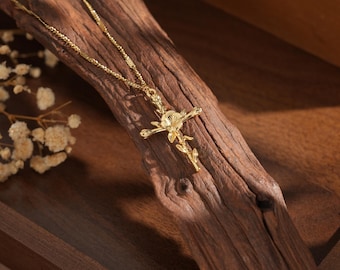 May include: A gold chain necklace with a floral cross pendant. The cross is made of gold and has a delicate floral design.