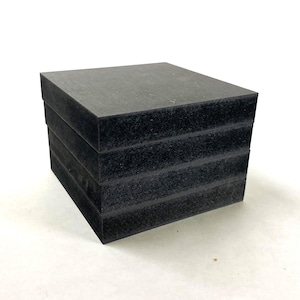 Könnte beinhalten: Ein Stapel aus vier schwarzen quadratischen Schaumstoffblöcken.