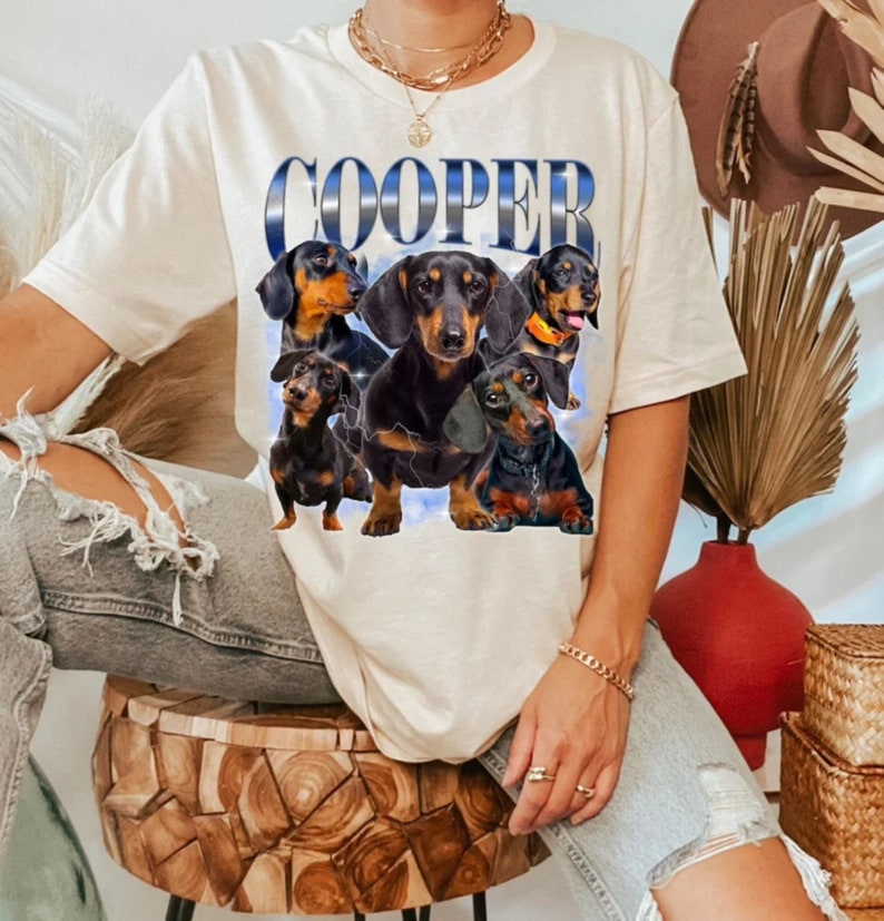 May include: A white t-shirt with the word "COOPER" printed in blue on the front. The shirt features a graphic of five dachshund dogs in various poses.