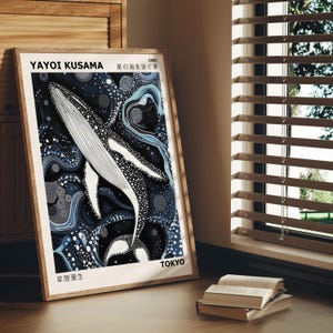 K&ouml;nnte beinhalten: Ein gerahmter Druck eines schwarz-wei&szlig;en Wals, der in einem blauen und wei&szlig;en abstrakten Muster schwimmt. Der Druck ist betitelt mit "Yayoi Kusama, Stern des Meeres, 1965, Tokio, Fr&uuml;he Werke".