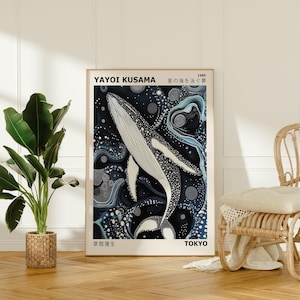 K&ouml;nnte beinhalten: Ein Poster mit einem schwarz-wei&szlig;en Wal, der in einem blauen und wei&szlig;en abstrakten Muster schwimmt. Das Poster ist gerahmt und hat unten den Text "YAYOI KUSAMA 1985 星の海を泳ぐ" und "東京 TOKYO".