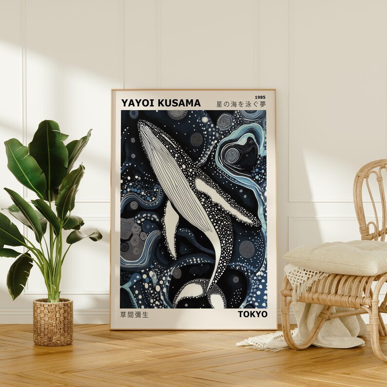 K&ouml;nnte beinhalten: Ein Poster mit einem schwarz-wei&szlig;en Wal, der in einem blauen und wei&szlig;en abstrakten Muster schwimmt. Das Poster ist gerahmt und hat unten den Text "YAYOI KUSAMA 1985 星の海を泳ぐ" und "東京 TOKYO".