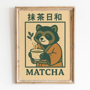Puede incluir: Impresión enmarcada con un mapache de dibujos animados con una túnica marrón sosteniendo una taza humeante de matcha. La imagen tiene texto japonés en la parte superior y la palabra "MATCHA" en la parte inferior, todo en verde y marrón.