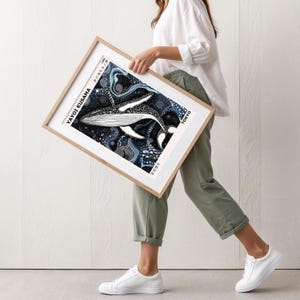 K&ouml;nnte beinhalten: Ein gerahmter Druck eines Wals, der in einem sternenklaren, wirbelnden Ozean schwimmt. Der Druck ist in Schwarz, Wei&szlig; und Blau gehalten und tr&auml;gt den Text "Yayoi Kusama" und "Tokyo".