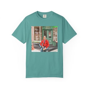 Illustrazione di un ritratto di Mr. Rogers seduto fuori da un bar, scena di strada, stampata su una maglietta. immagine 8