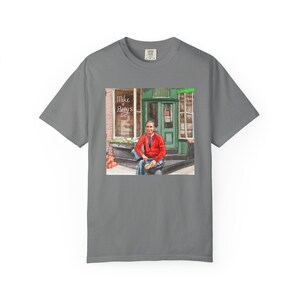Illustrazione di un ritratto di Mr. Rogers seduto fuori da un bar, scena di strada, stampata su una maglietta. immagine 5