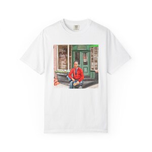 Illustrazione di un ritratto di Mr. Rogers seduto fuori da un bar, scena di strada, stampata su una maglietta. immagine 2