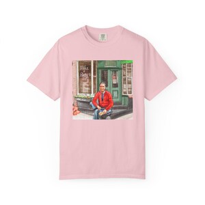 Illustrazione di un ritratto di Mr. Rogers seduto fuori da un bar, scena di strada, stampata su una maglietta. immagine 11