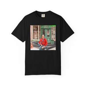 Illustrazione di un ritratto di Mr. Rogers seduto fuori da un bar, scena di strada, stampata su una maglietta. immagine 9
