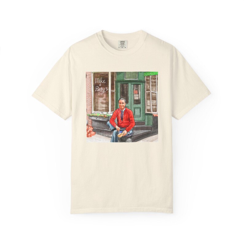 Illustrazione di un ritratto di Mr. Rogers seduto fuori da un bar, scena di strada, stampata su una maglietta. immagine 3