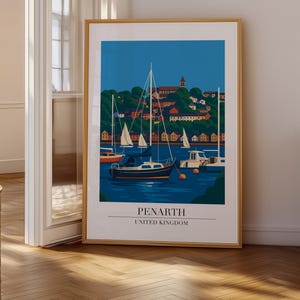 May include: A framed art print of Penarth, United Kingdom, featuring a harbor scene with sailboats and a town in the background. The artwork has a blue sky and water, with a wooden frame.