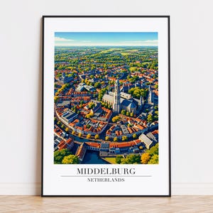May include: An aerial view of Middelburg, Netherlands, framed in a black border. The image showcases a vibrant cityscape with red-tiled roofs, a prominent church, and lush green trees under a clear blue sky. The text "MIDDELBURG NETHERLANDS" is at the bottom.