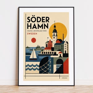 May include: A framed travel poster featuring a stylized illustration of Söderhamn, Sweden. The artwork displays a coastal town with a church tower, a sailboat on blue water, a red sun, and a fishing net. The text reads SÖDER HAMN, SWEDEN.