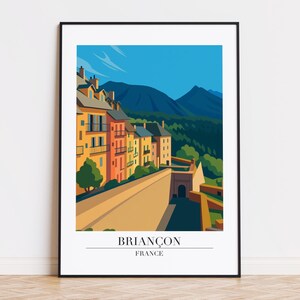 May include: A framed art print featuring a stylized illustration of Briançon, France. The artwork depicts colorful buildings, a stone wall, and mountains under a blue sky. The text "Briançon France" is at the bottom.
