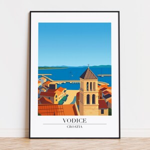 May include: A framed art print featuring a stylized illustration of Vodice, Croatia. The image depicts a coastal town with a church tower, red-tiled roofs, and a blue sea under a clear sky. The text "VODICE CROATIA" is at the bottom.