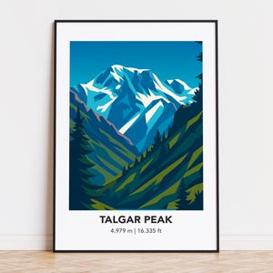 Puede incluir: Una impresión artística enmarcada que presenta una ilustración estilizada del pico Talgar. La obra de arte representa una cordillera con picos nevados, sobre un cielo azul. El texto "TALGAR PEAK" se muestra debajo de la imagen, junto con la altura: 4.979 m | 16.335 pies.