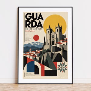 May include: A framed travel poster featuring a stylised illustration of the city of Guarda, Portugal. The artwork depicts a cathedral, mountains, and geometric shapes in a palette of cream, black, red, blue, and yellow, with the text GUARDA.