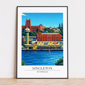 Puede incluir: Una impresión artística enmarcada de Singleton, Australia, con una colorida ilustración de una escena frente al mar. La obra de arte representa edificios en tonos rojos, amarillos y verdes, con un río y cielo azules. El texto "SINGLETON AUSTRALIA" se muestra en la parte inferior.
