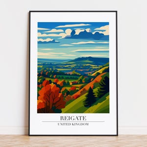 May include: A framed art print featuring a stylized landscape of Reigate, United Kingdom. The artwork depicts rolling green hills, colorful trees, and a blue sky with clouds. The text "REIGATE UNITED KINGDOM" is at the bottom.
