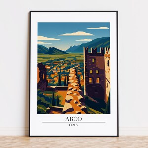 以下が含まれることがあります： イタリアのアルコをスタイリッシュに描いた、額入りのアートプリント。谷間の町へと続く石畳の道と、背景には山々が描かれています。プリントには「ARCO ITALY」の文字が含まれています。