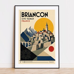 May include: A framed travel poster featuring a stylized illustration of Briancon, Cite Vauban, France. The artwork depicts a hilltop town with a church tower, snow-capped mountains, a bridge, a large yellow sun, and a red circle on a cream background.