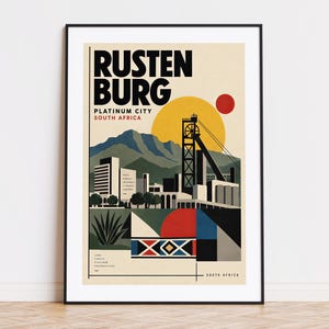 以下が含まれることがあります： RUSTENBURG PLATINUM CITY SOUTH AFRICAという文字が入った額装されたトラベルポスター。グラフィックイラストには、鉱山の櫓、黄色い太陽、赤い円、山々、建物が黒、黄色、赤、青の色調で描かれています。