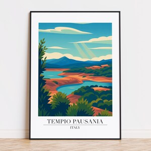 May include: A framed art print featuring a stylized landscape of Tempio Pausania, Italy. The artwork depicts a serene scene with a blue lake, green foliage, and mountains under a bright sky with sun rays. The text "TEMPIO PAUSANIA ITALY" is at the bottom.