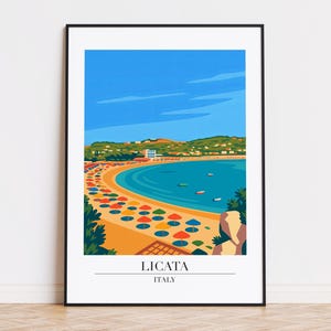 May include: A framed art print featuring a stylized coastal scene of Licata, Italy. The artwork depicts a beach with colorful umbrellas, turquoise water, and a town nestled in green hills under a blue sky. The text "LICATA ITALY" is at the bottom.