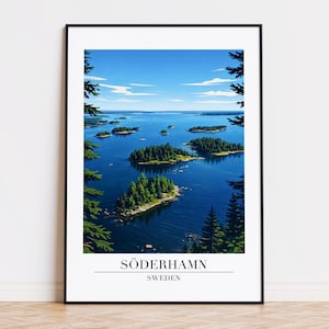 May include: Framed art print featuring a scenic view of Söderhamn, Sweden. The artwork depicts a blue lake dotted with small islands covered in green trees, under a bright blue sky. The text "SÖDERHAMN SWEDEN" is printed at the bottom.