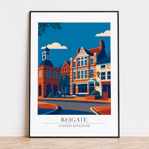 May include: A framed art print featuring a stylized illustration of Reigate, United Kingdom. The artwork depicts buildings in shades of orange, red, and white against a blue sky. The text "REIGATE UNITED KINGDOM" is at the bottom.